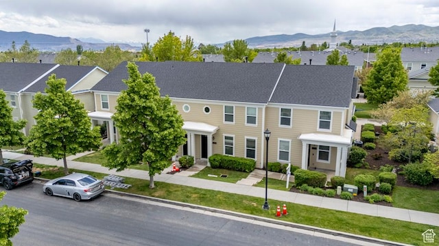 view of property featuring a mountain view, a front yard, and a residential view