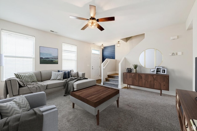 living room featuring a ceiling fan, carpet floors, and stairway