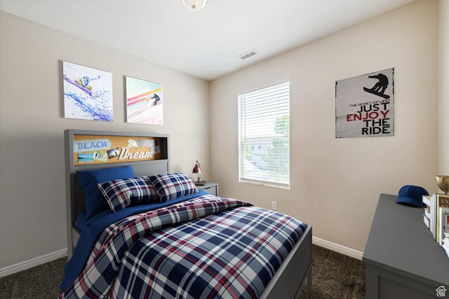 bedroom with dark colored carpet and baseboards