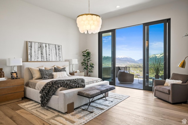 bedroom with access to exterior, a mountain view, hardwood / wood-style floors, recessed lighting, and a chandelier