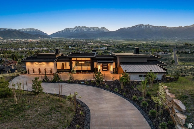 view of front of home with a mountain view, curved driveway, and a chimney