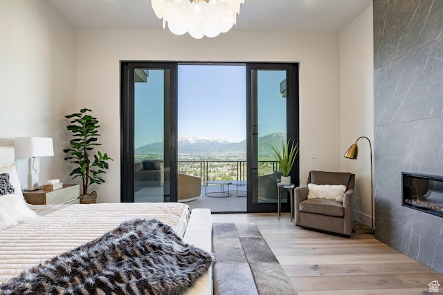 1964 E Upper Lookout Knoll Cir Unit 371, Heber City, UT 84032 - bedroom with access to outside, wood finished floors, a tiled fireplace, a mountain view, and a chandelier