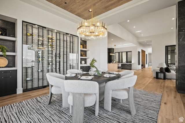 dining room featuring a chandelier, wood finished floors, recessed lighting, and a raised ceiling