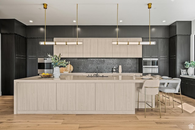 kitchen with a sink, modern cabinets, tasteful backsplash, light countertops, and a spacious island