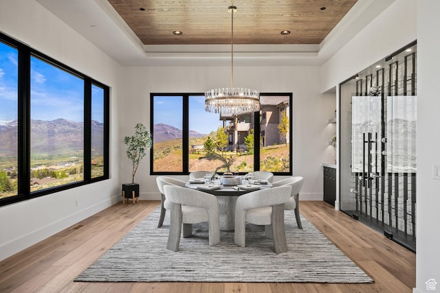 dining room featuring wooden ceiling, a tray ceiling, a chandelier, wood finished floors, and a mountain view