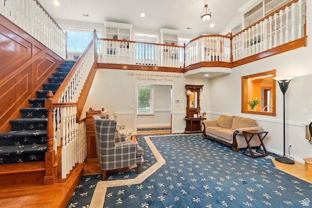 living area featuring wood finished floors, stairs, baseboards, recessed lighting, and a towering ceiling