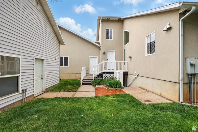 rear view of house with a lawn and stucco siding