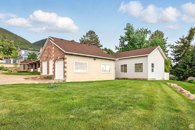 rear view of house featuring a yard, an attached garage, driveway, and a mountain view