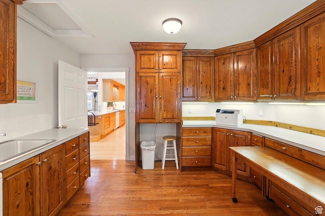 kitchen featuring wood finished floors, brown cabinets, and light countertops