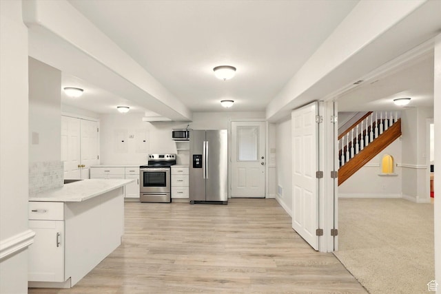 kitchen featuring appliances with stainless steel finishes, white cabinetry, light countertops, and light wood-type flooring