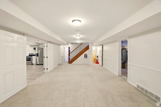 finished basement featuring stainless steel refrigerator with ice dispenser, stairs, baseboards, and light carpet
