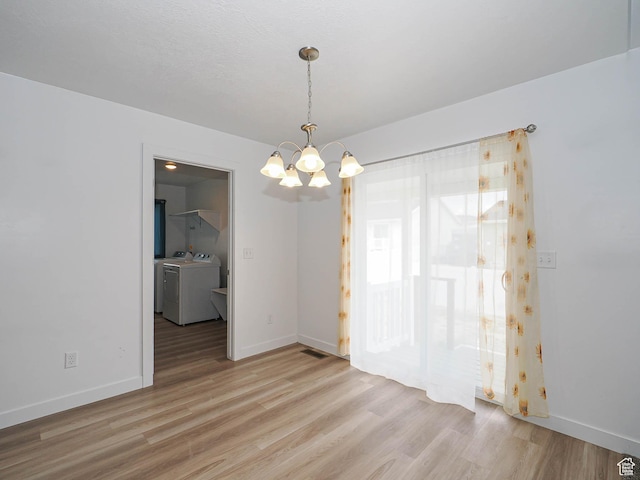 empty room with washer and clothes dryer, a chandelier, light wood finished floors, and baseboards