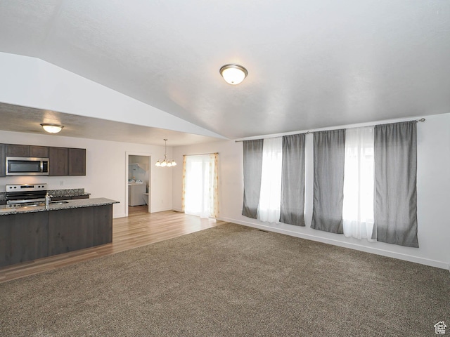 unfurnished living room with washer / clothes dryer, a chandelier, lofted ceiling, light carpet, and baseboards
