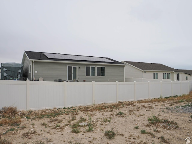 view of side of home featuring solar panels and fence