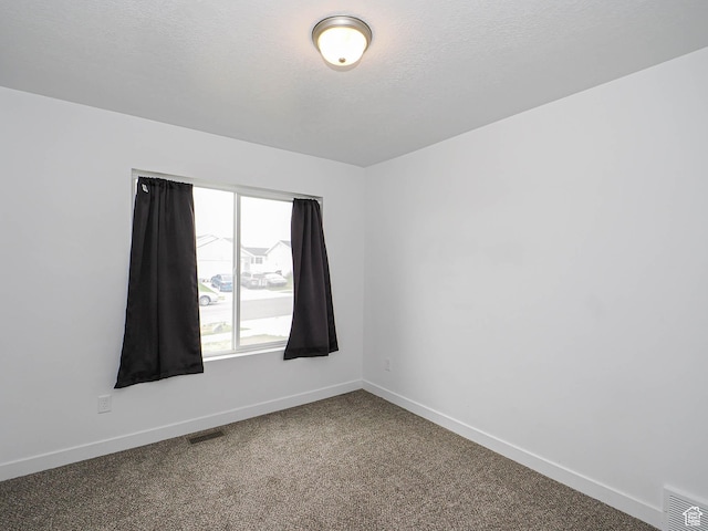 carpeted spare room with baseboards and a textured ceiling