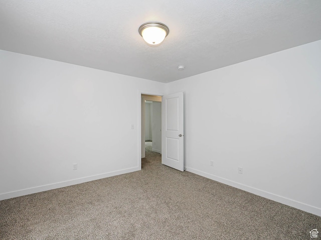 carpeted empty room featuring baseboards and a textured ceiling