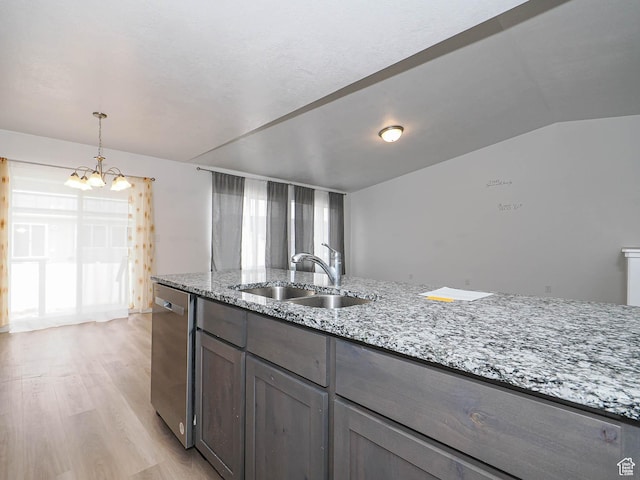 kitchen featuring stainless steel dishwasher, a sink, light wood-type flooring, a chandelier, and light stone counters