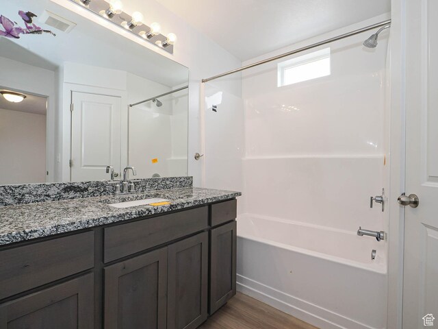full bathroom featuring wood finished floors, washtub / shower combination, and vanity