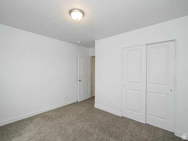 unfurnished bedroom with carpet floors, baseboards, a closet, and a textured ceiling
