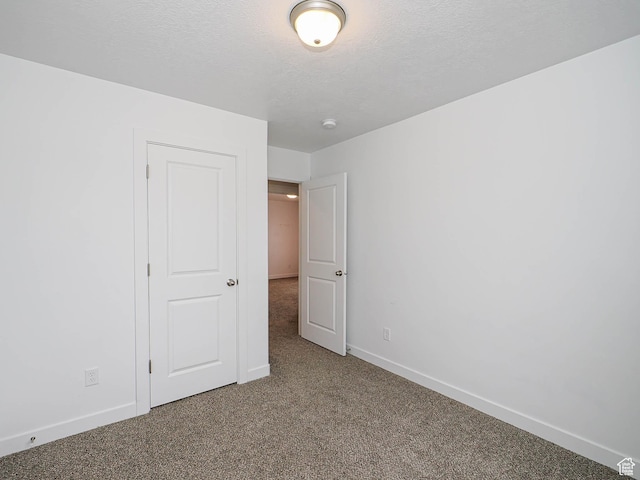 unfurnished bedroom featuring carpet flooring, a textured ceiling, and baseboards