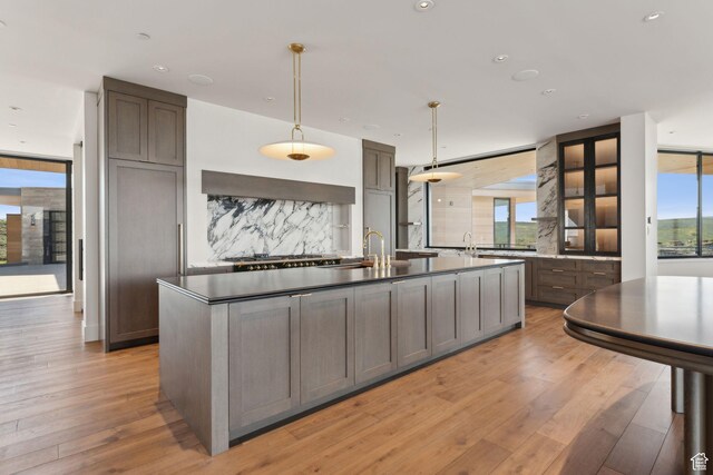 7455 N Promontory Ranch Rd, Park City, UT 84098 - kitchen with decorative backsplash, light wood-style floors, a center island with sink, recessed lighting, and a sink