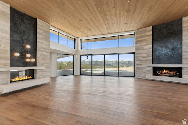 7455 N Promontory Ranch Rd, Park City, UT 84098 - unfurnished living room featuring a fireplace, a towering ceiling, wood ceiling, plenty of natural light, and hardwood / wood-style flooring