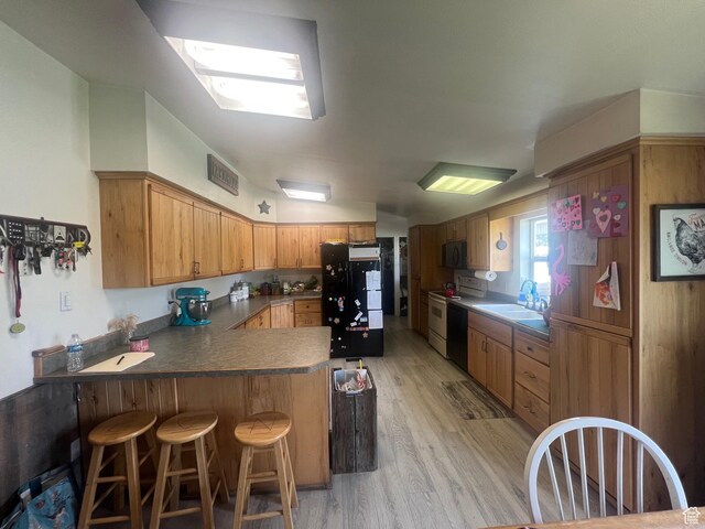 465 E Kings Ln, Green River, UT 84525 - kitchen featuring black appliances, a sink, a peninsula, light wood-style floors, and a breakfast bar