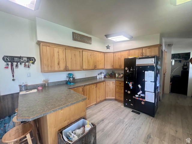 465 E Kings Ln, Green River, UT 84525 - kitchen with black refrigerator with ice dispenser, a peninsula, light wood-style flooring, and dark countertops