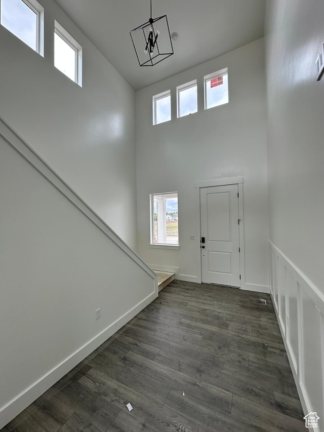 entrance foyer featuring a high ceiling, dark wood finished floors, a chandelier, and baseboards