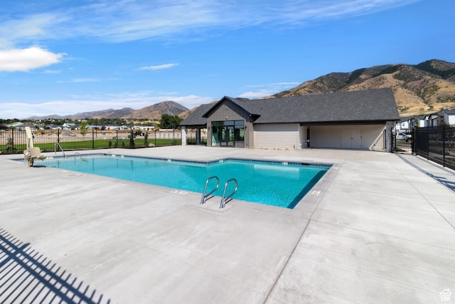 community pool featuring a mountain view, fence, and a patio