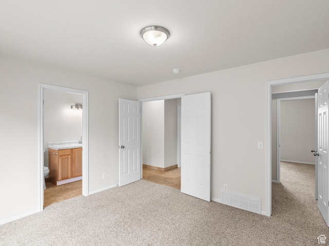 unfurnished bedroom with light carpet, baseboards, and connected bathroom
