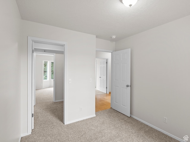 unfurnished bedroom with light carpet, baseboards, and a textured ceiling