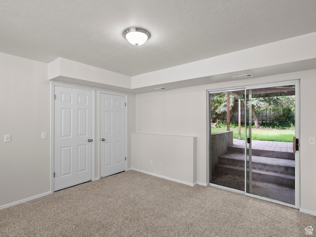 unfurnished bedroom featuring access to outside, carpet, baseboards, a textured ceiling, and a closet