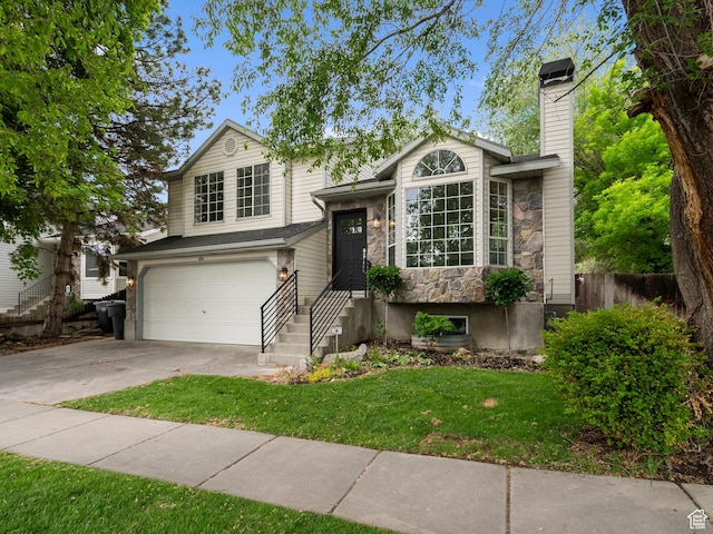 split level home with stone siding, a garage, concrete driveway, and a chimney