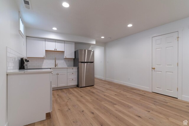 158 N State St, Salt Lake City, UT 84103 - kitchen featuring freestanding refrigerator, white cabinetry, light wood finished floors, light countertops, and backsplash