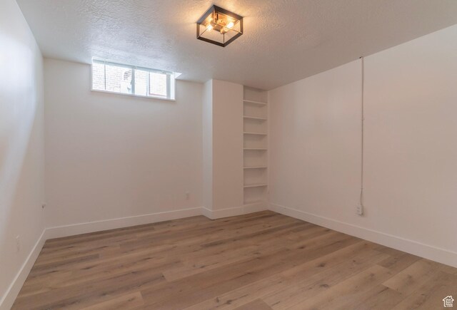158 N State St, Salt Lake City, UT 84103 - basement featuring light wood-style flooring, a textured ceiling, and baseboards