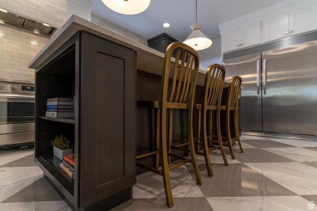 158 N State St, Salt Lake City, UT 84103 - kitchen with stainless steel built in refrigerator, oven, white cabinets, marble finish flooring, and hanging light fixtures