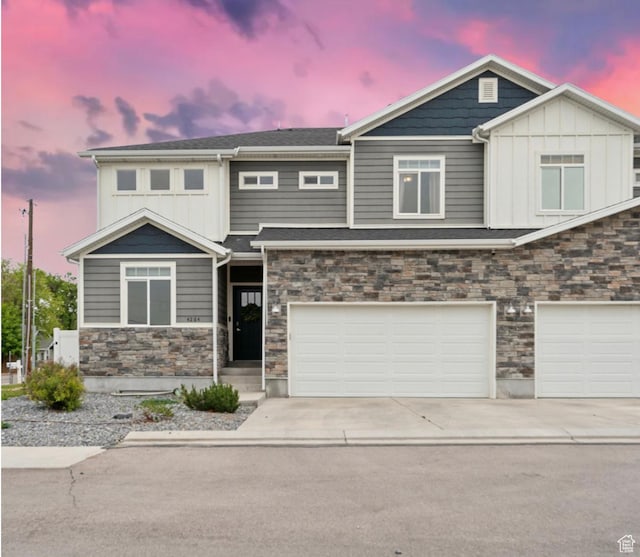 view of front facade featuring stone siding, driveway, an attached garage, and board and batten siding