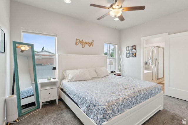 bedroom with dark colored carpet, ensuite bath, and ceiling fan