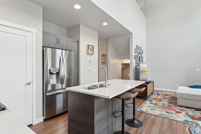 kitchen featuring stainless steel fridge, a sink, modern cabinets, a kitchen breakfast bar, and dark wood-style floors