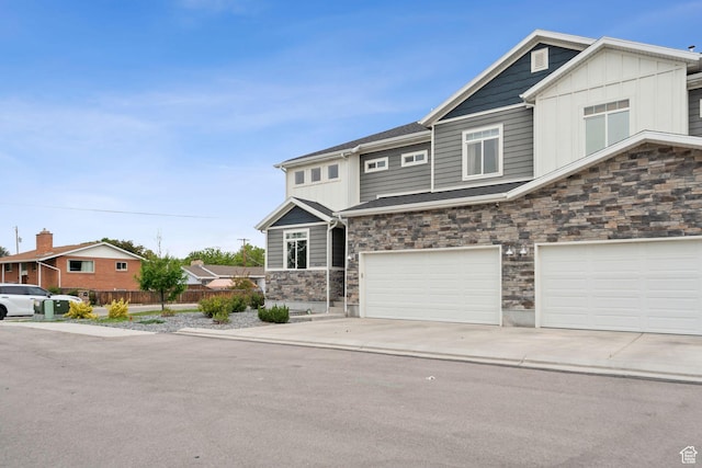 view of front of house featuring stone siding, an attached garage, board and batten siding, and concrete driveway