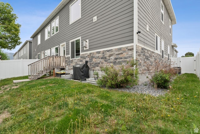 rear view of property featuring stone siding and a gate
