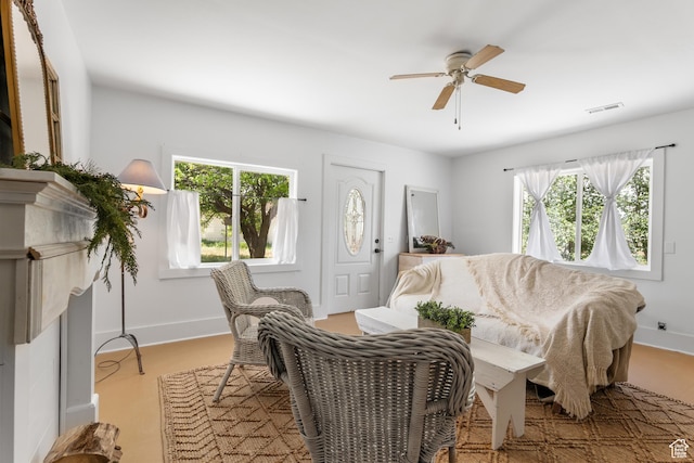 living area with plenty of natural light, a ceiling fan, and baseboards