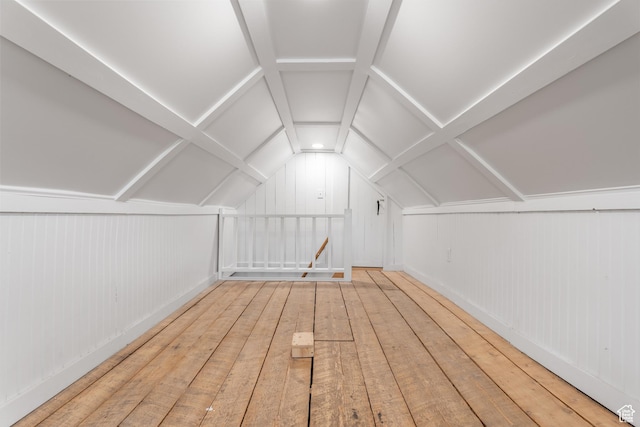 bonus room featuring lofted ceiling, hardwood / wood-style floors, and wooden walls