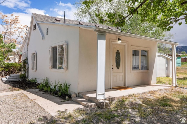 view of front of house with stucco siding and roof with shingles