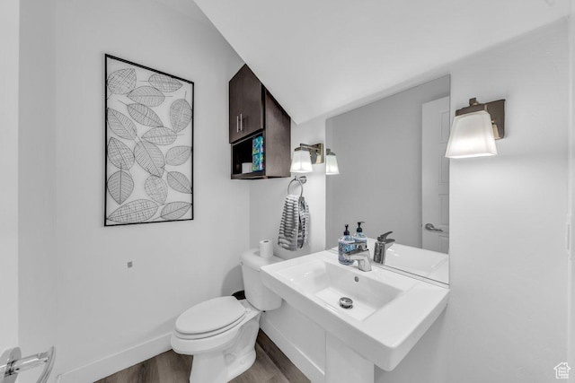 bathroom with wood finished floors, a sink, toilet, and baseboards