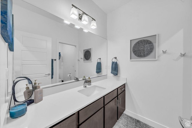bathroom with toilet, vanity, and baseboards