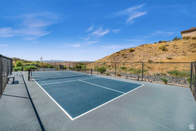 view of tennis court with fence and a mountain view