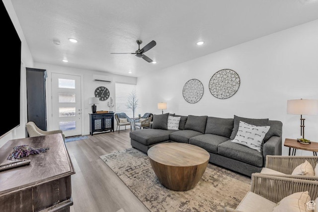 living area with a ceiling fan, wood finished floors, recessed lighting, and a wall unit AC