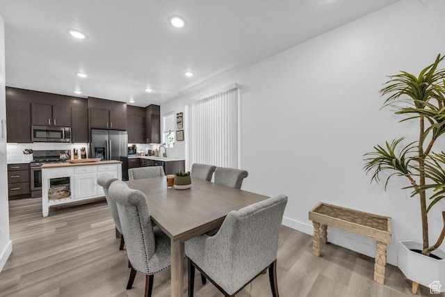 dining room with light wood finished floors, baseboards, and recessed lighting